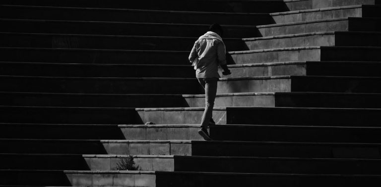 Eine Person geht eine dunkle Treppe hinauf.