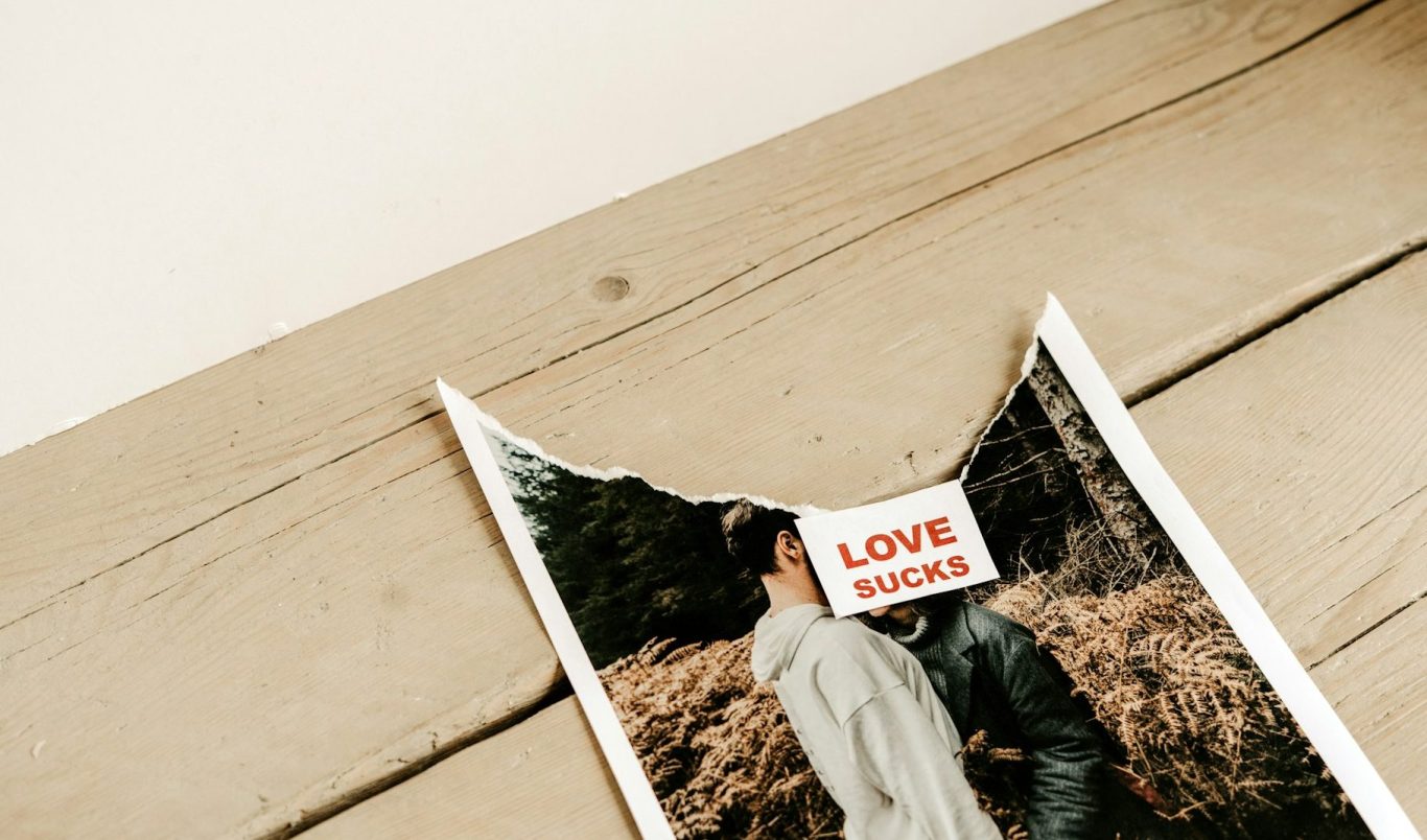 Ein zerrissenes Foto eines Paares mit dem Schriftzug "LOVE" darauf.